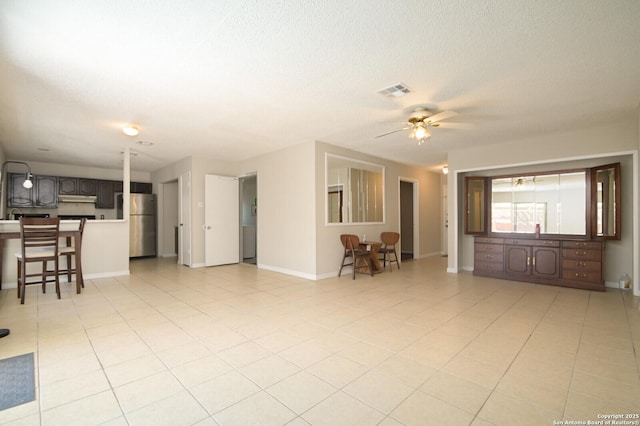 living room with ceiling fan, a textured ceiling, and light tile patterned floors