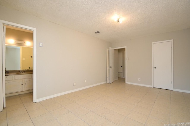 unfurnished bedroom featuring a textured ceiling, ensuite bathroom, and sink