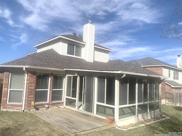 rear view of property featuring a wooden deck, a yard, and a sunroom