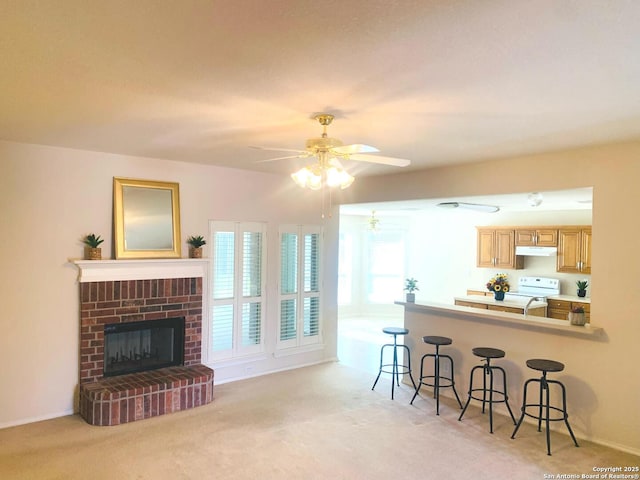 carpeted living room with a brick fireplace, ceiling fan, and sink