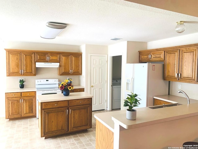 kitchen featuring washer / dryer, white appliances, a textured ceiling, and sink