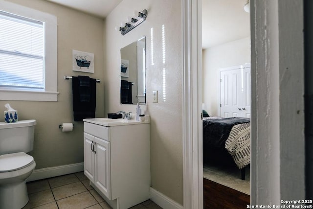 bathroom with toilet, vanity, and tile patterned flooring