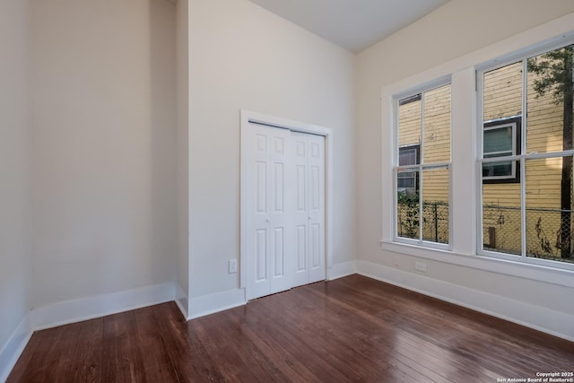 unfurnished bedroom with a closet and dark hardwood / wood-style flooring