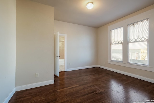 empty room featuring plenty of natural light and dark hardwood / wood-style floors