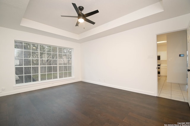 spare room with ceiling fan, hardwood / wood-style flooring, and a tray ceiling