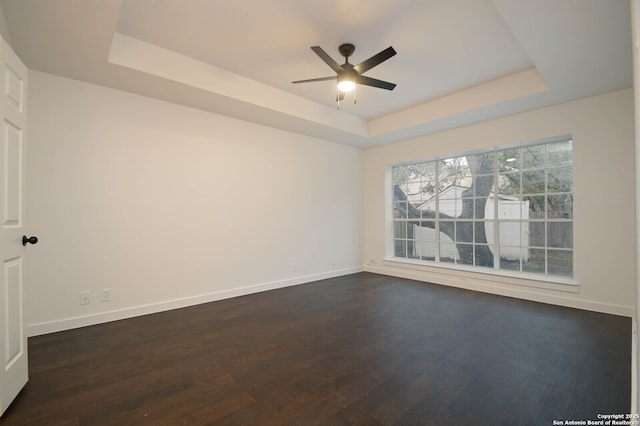 empty room featuring ceiling fan, dark hardwood / wood-style flooring, and a raised ceiling