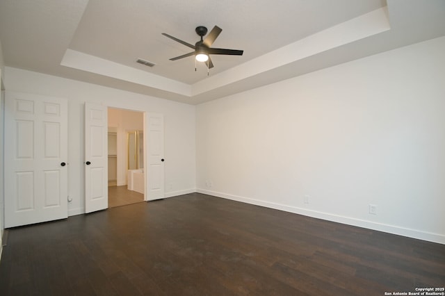 spare room with dark wood-type flooring, ceiling fan, and a tray ceiling