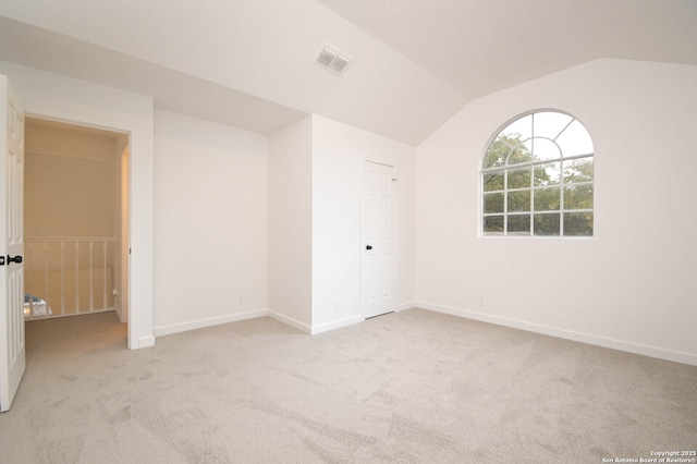 unfurnished room with light colored carpet and vaulted ceiling