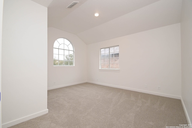 carpeted spare room with vaulted ceiling