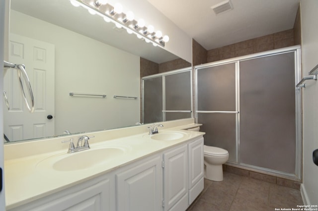 bathroom featuring toilet, tile patterned floors, a shower with shower door, and vanity