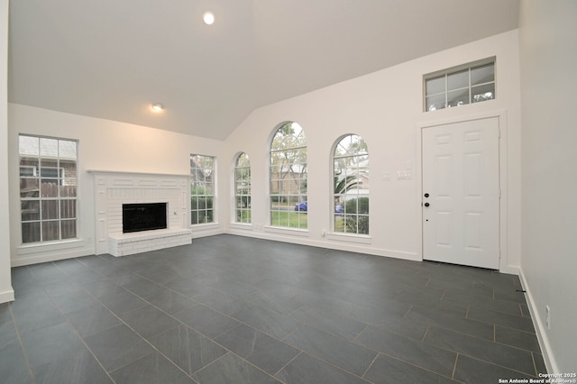 unfurnished living room featuring dark tile patterned floors, vaulted ceiling, and a fireplace