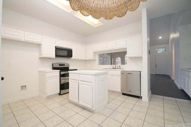 kitchen with a kitchen island, sink, light tile patterned floors, appliances with stainless steel finishes, and white cabinets