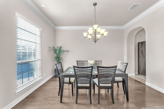 dining area with a wealth of natural light, hardwood / wood-style flooring, a chandelier, and ornamental molding