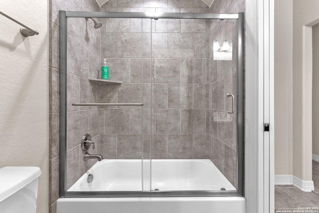 bathroom featuring bath / shower combo with glass door and toilet