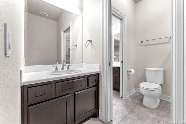 bathroom with toilet, vanity, and tile patterned floors