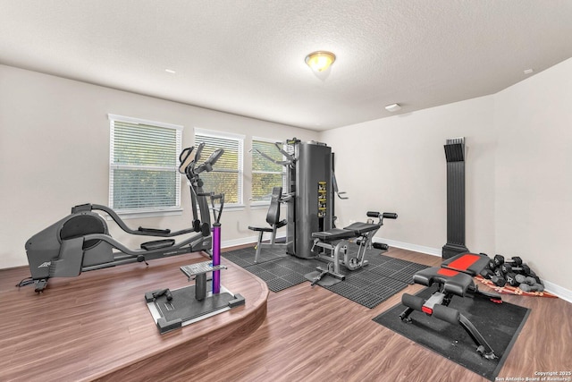 workout area with dark wood-type flooring and a textured ceiling