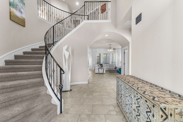 tiled foyer entrance with ceiling fan and a high ceiling