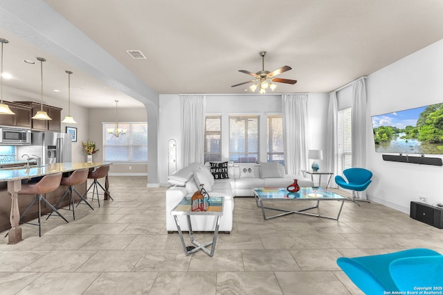 living room with ceiling fan with notable chandelier and sink