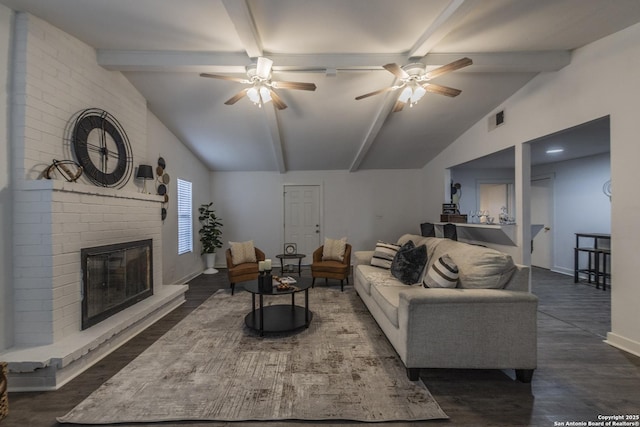 living room with a brick fireplace, dark hardwood / wood-style flooring, ceiling fan, and vaulted ceiling with beams