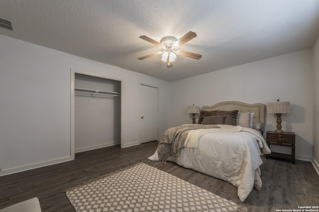 bedroom with ceiling fan, a textured ceiling, dark hardwood / wood-style floors, and a closet