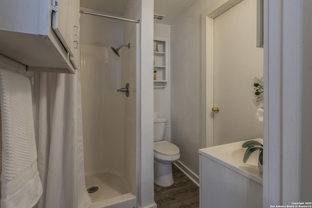 bathroom with toilet, wood-type flooring, vanity, and curtained shower