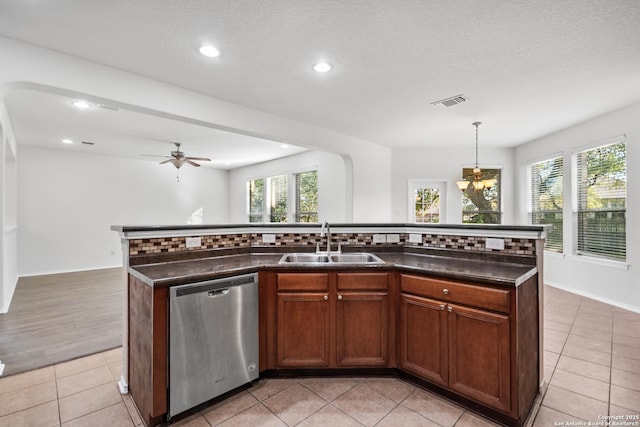 kitchen featuring stainless steel dishwasher, decorative light fixtures, a kitchen island with sink, ceiling fan with notable chandelier, and sink