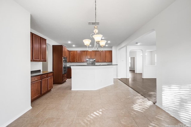 kitchen featuring an inviting chandelier, light tile patterned floors, stainless steel double oven, pendant lighting, and a center island