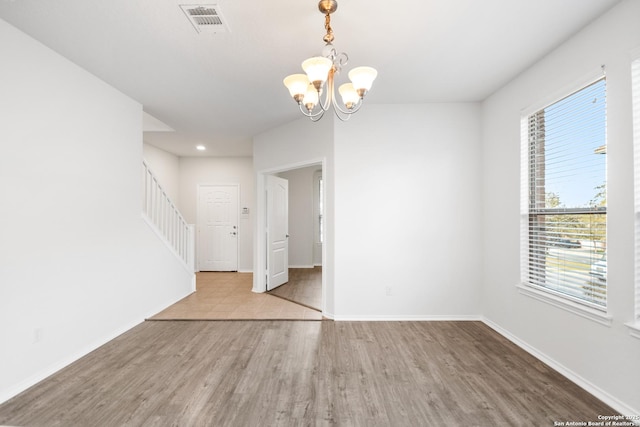 unfurnished room featuring light hardwood / wood-style flooring and a chandelier