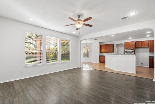 unfurnished living room featuring dark wood-type flooring and ceiling fan with notable chandelier