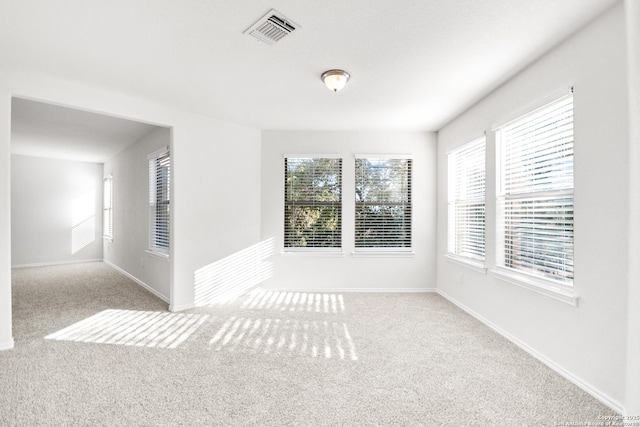 unfurnished room featuring plenty of natural light and light carpet