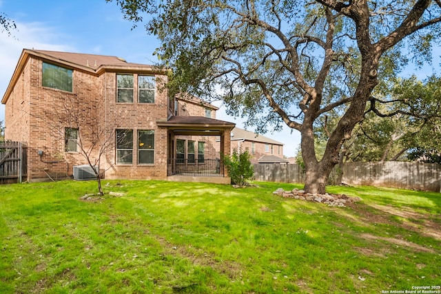 rear view of property featuring central AC and a lawn