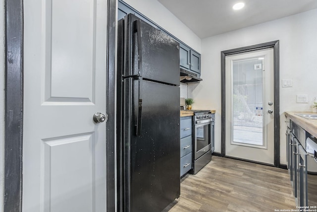 kitchen featuring stainless steel stove, black fridge, butcher block counters, and hardwood / wood-style floors