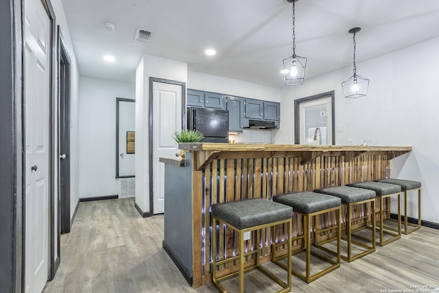 kitchen with decorative light fixtures, kitchen peninsula, blue cabinets, and a breakfast bar area