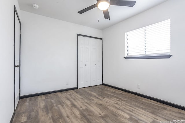 unfurnished bedroom featuring ceiling fan, dark wood-type flooring, and a closet