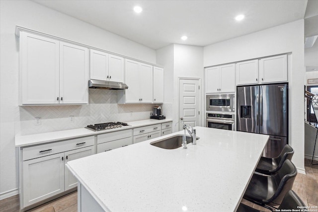 kitchen featuring sink, a kitchen breakfast bar, appliances with stainless steel finishes, and a center island with sink