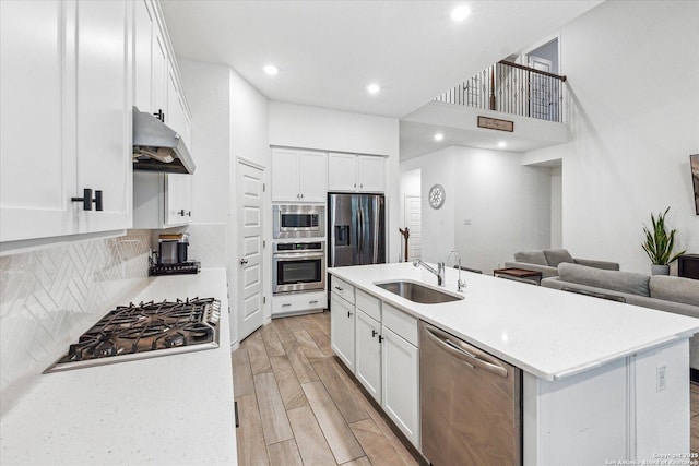 kitchen with an island with sink, white cabinets, sink, and stainless steel appliances