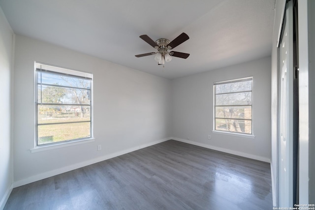 empty room featuring ceiling fan, a wealth of natural light, and dark hardwood / wood-style flooring