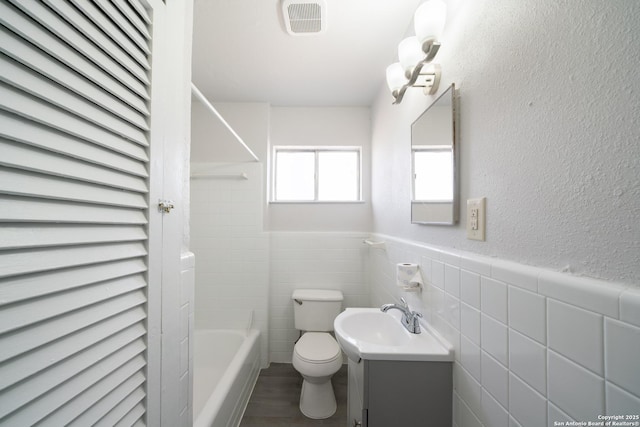 full bathroom featuring shower / bath combination, toilet, vanity, and tile walls