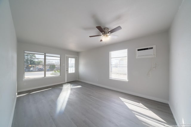 empty room featuring an AC wall unit, hardwood / wood-style floors, and ceiling fan