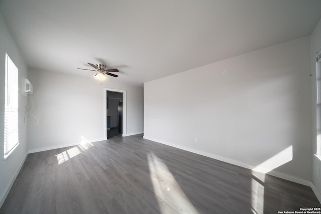 spare room featuring ceiling fan, dark hardwood / wood-style flooring, a wealth of natural light, and a wall unit AC