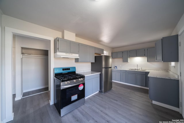 kitchen with dark wood-type flooring, stainless steel appliances, gray cabinets, and sink