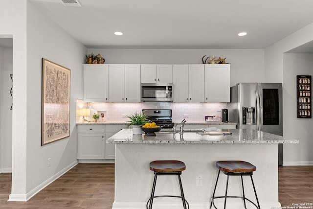 kitchen featuring white cabinets, appliances with stainless steel finishes, and a center island with sink