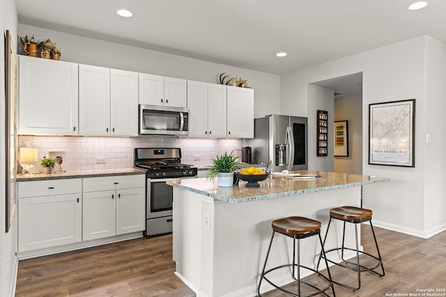 kitchen with white cabinets, stainless steel appliances, and a kitchen island with sink