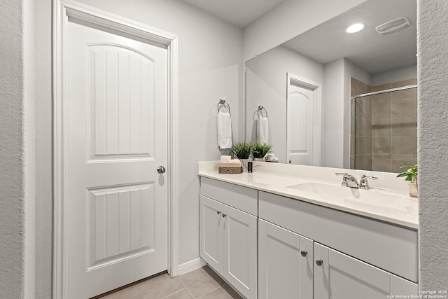 bathroom with a shower with shower door, vanity, and tile patterned floors