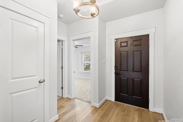 foyer with light wood-type flooring and a notable chandelier