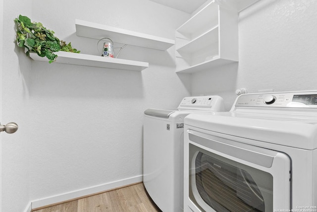 clothes washing area featuring washer and clothes dryer and light hardwood / wood-style floors