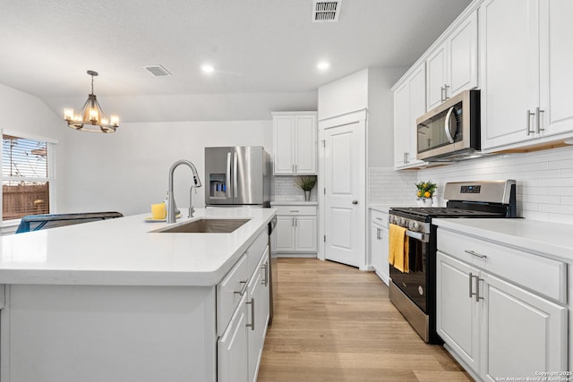 kitchen featuring white cabinetry, stainless steel appliances, a center island with sink, and sink