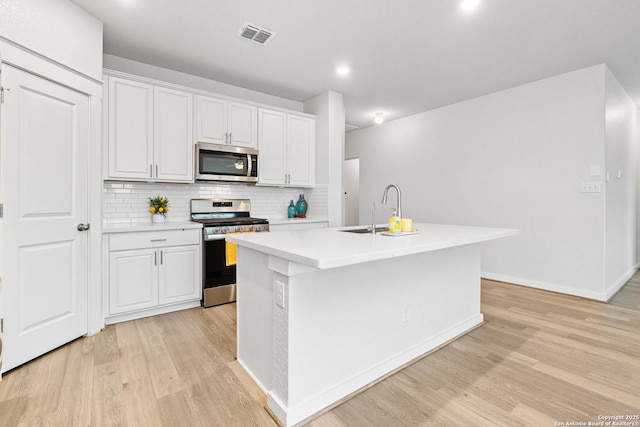 kitchen with sink, white cabinetry, stainless steel appliances, and an island with sink