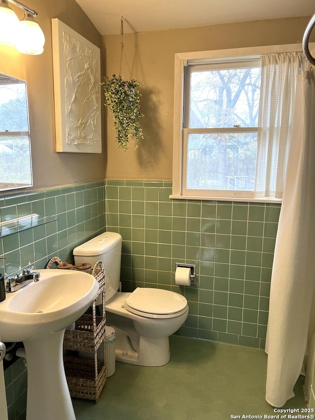 bathroom featuring sink, toilet, tile patterned floors, and tile walls