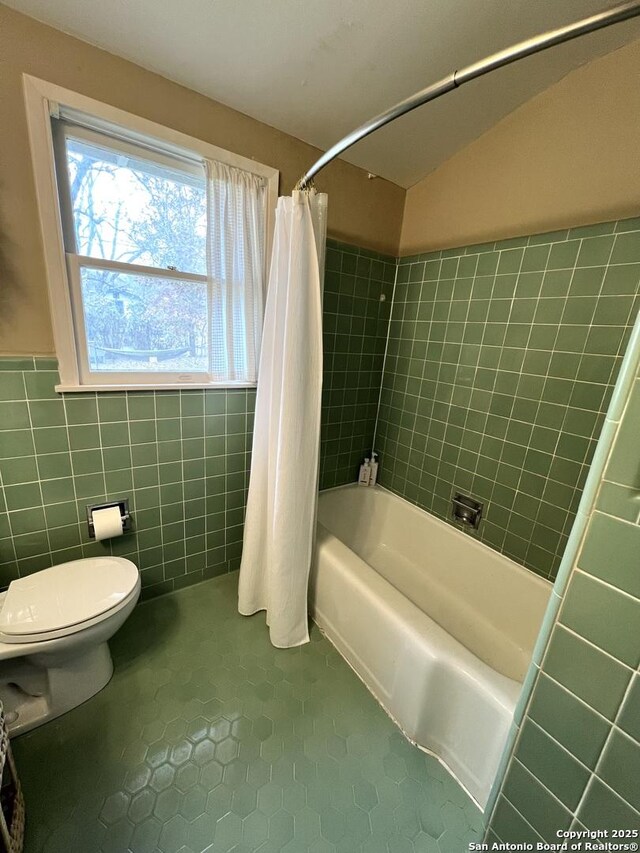 bathroom with shower / bath combo with shower curtain, tile walls, toilet, and tile patterned flooring